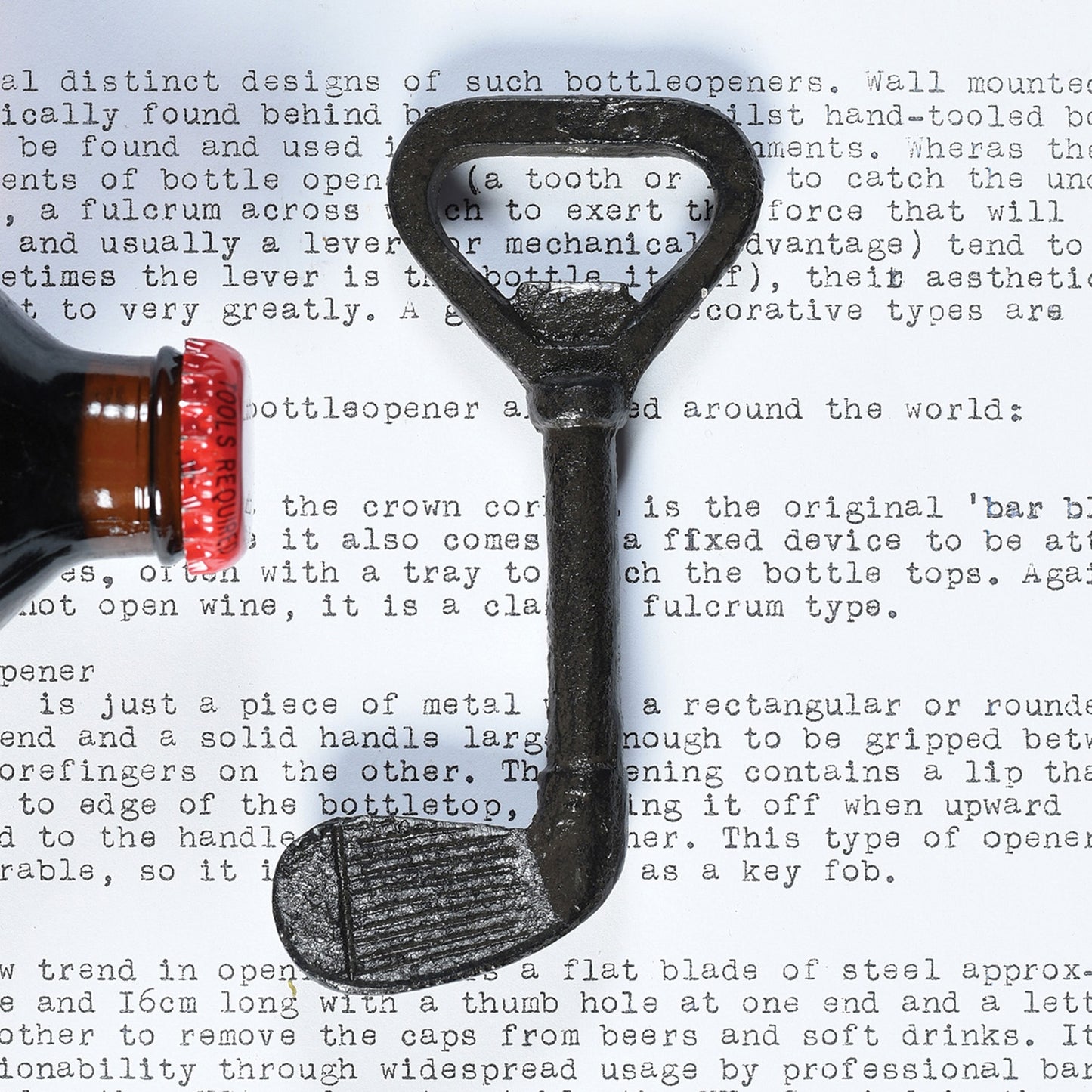 Image of a cast iron golf club bottle opener next to a bottle cap.