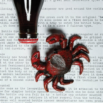 Image of a red cast iron crab bottle opener next to a bottle cap.